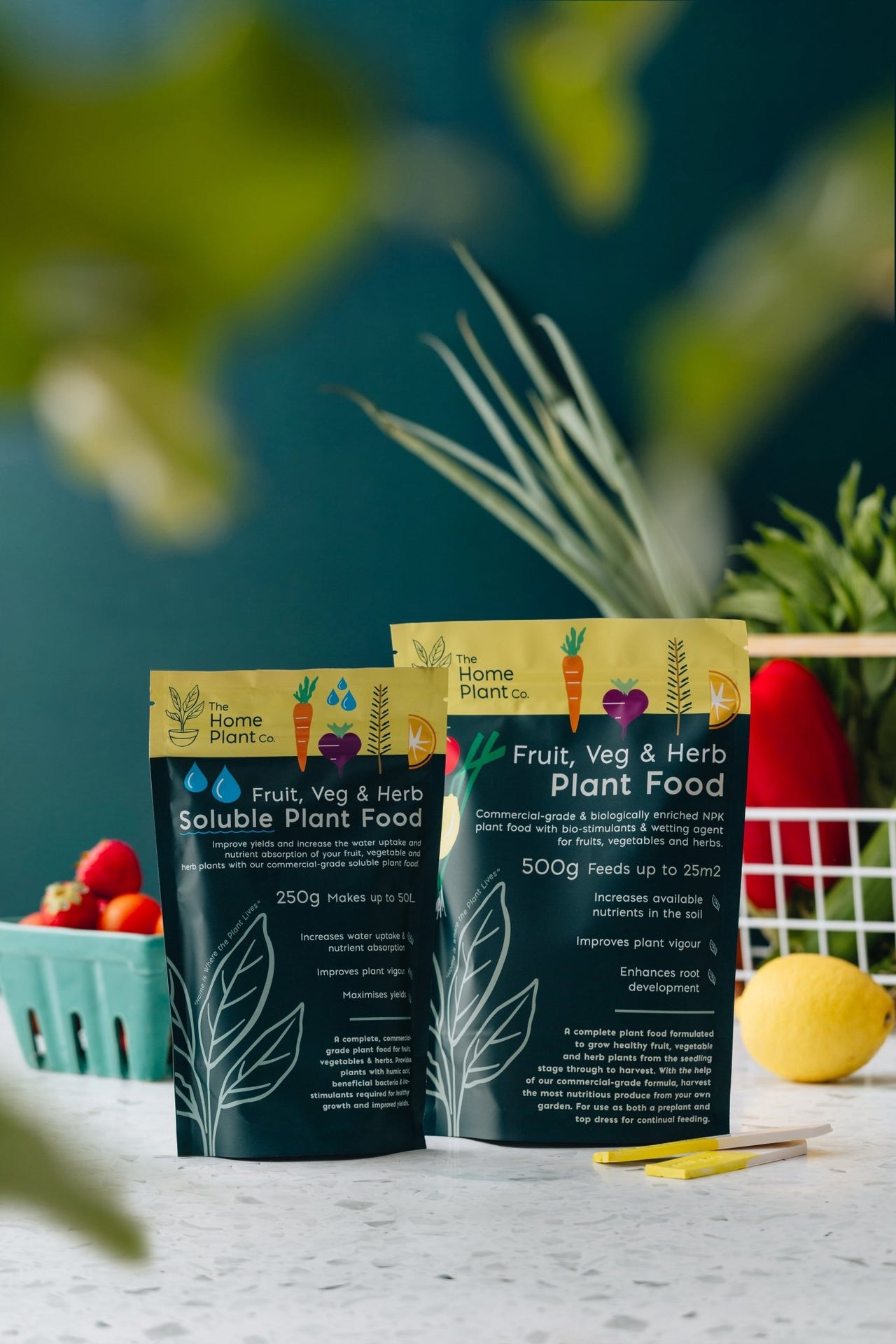 Fruit, Veg & Herb fertiliser packets sitting on a bench next to a basket of vegetables.